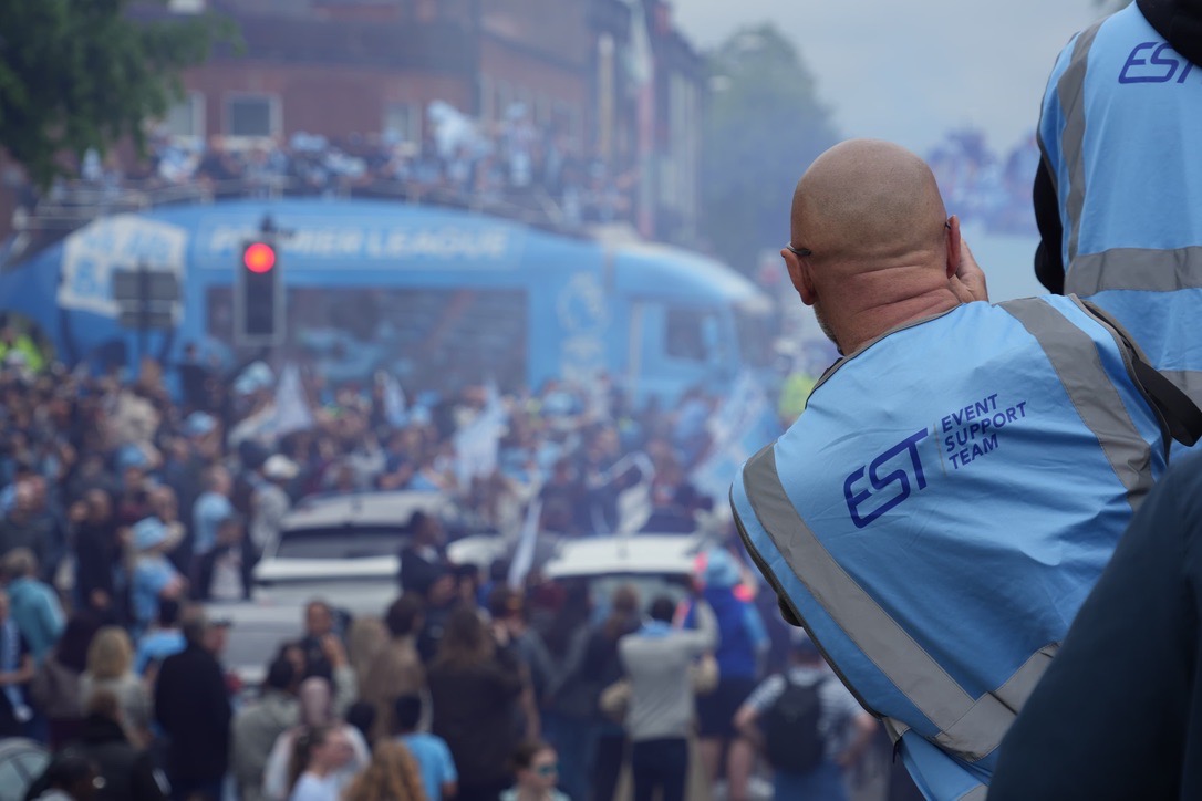 An Event Support Team steward overseeing the packed Coventry parade route as the open-top bus passes